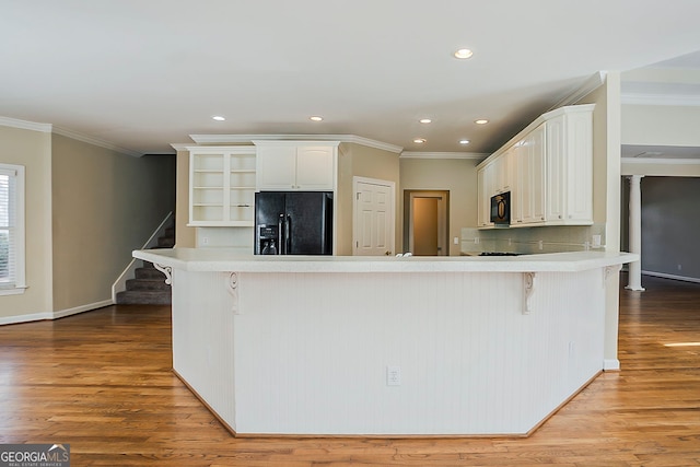 1621 Annapolis Way, Grayson, GA 30017 - kitchen with wood finished floors, a peninsula, black appliances, a kitchen bar, and crown molding