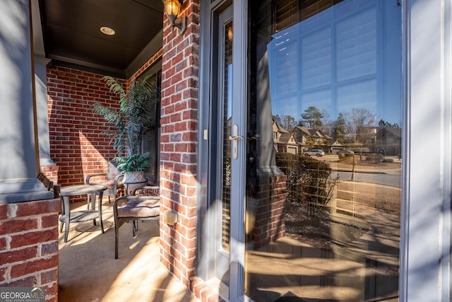 view of exterior entry featuring covered porch and brick siding