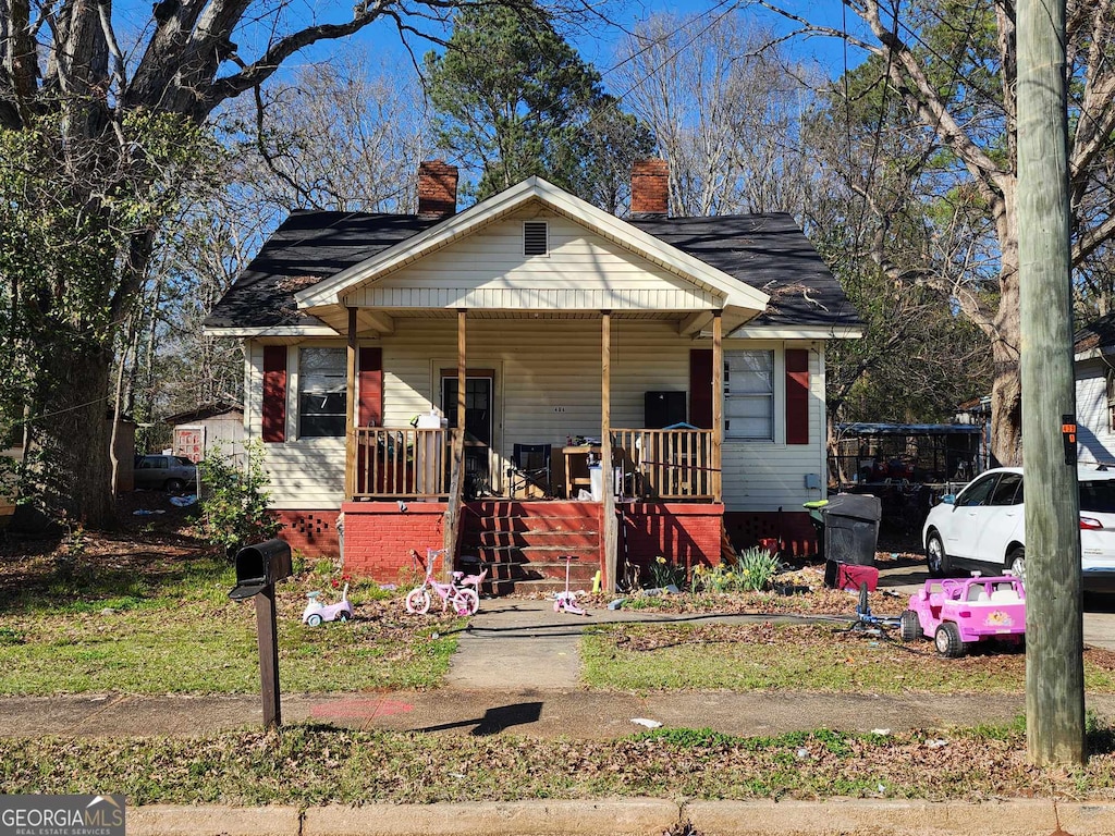 bungalow-style house with covered porch and a chimney