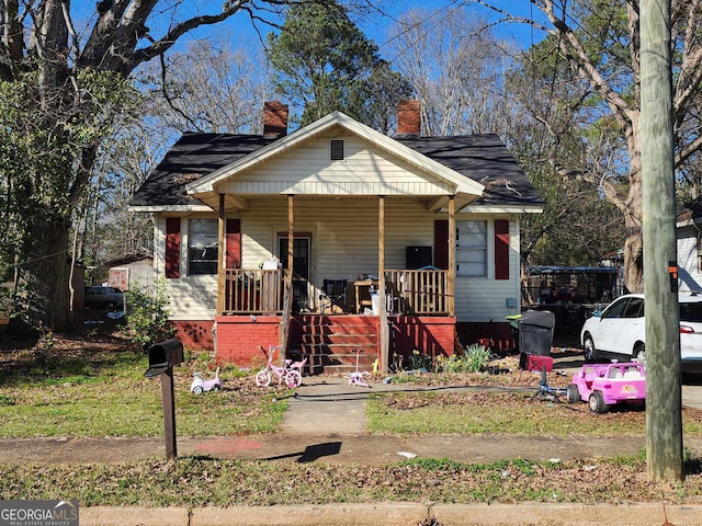 bungalow-style house with covered porch and a chimney