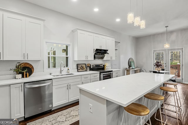 kitchen featuring a kitchen island, a breakfast bar, stainless steel appliances, white cabinetry, and a sink