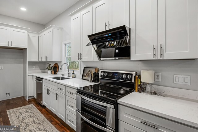 kitchen featuring a sink, range hood, white cabinetry, appliances with stainless steel finishes, and dark wood-style flooring