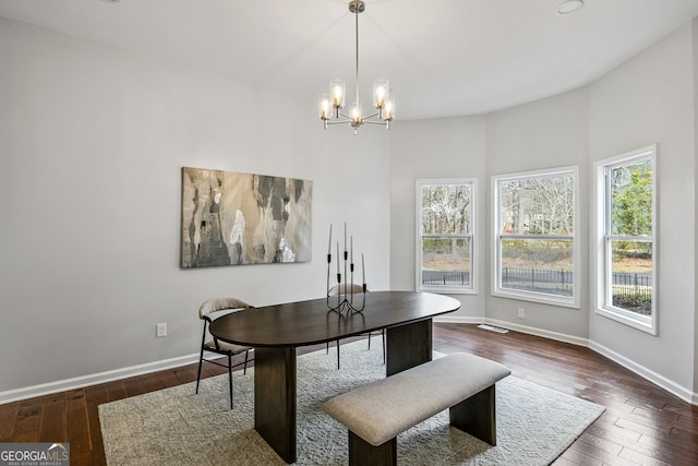 dining space featuring dark wood finished floors, an inviting chandelier, and baseboards