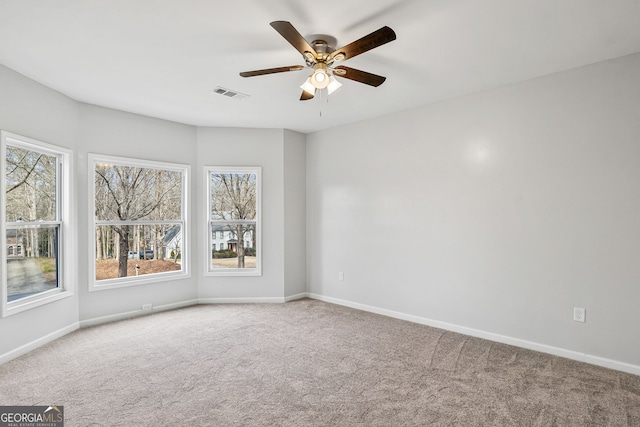 carpeted spare room featuring visible vents, a ceiling fan, and baseboards