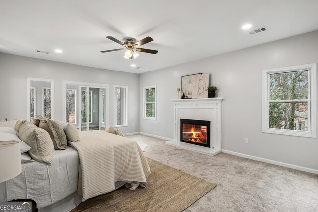 bedroom featuring a glass covered fireplace, baseboards, visible vents, and light carpet