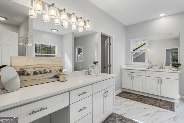 full bath with a sink, two vanities, marble finish floor, and a walk in shower