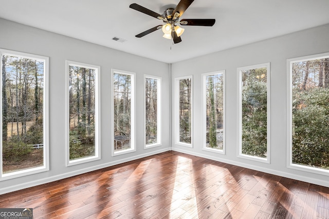 unfurnished sunroom with visible vents, a healthy amount of sunlight, and a ceiling fan