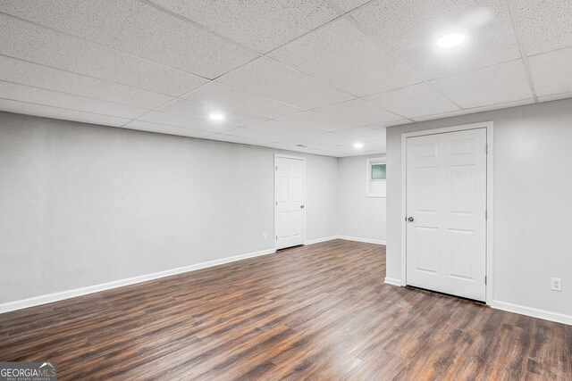 finished basement featuring recessed lighting, dark wood-style floors, baseboards, and a paneled ceiling