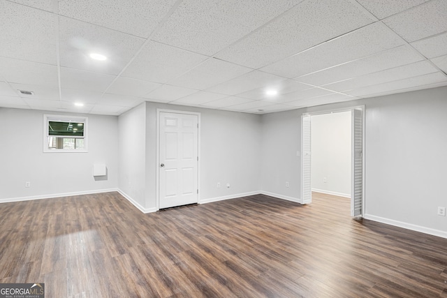 basement with visible vents, a paneled ceiling, baseboards, and dark wood-style flooring