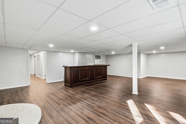 finished below grade area with visible vents, baseboards, dark wood finished floors, a drop ceiling, and recessed lighting