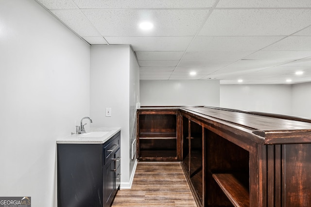 bar with wood finished floors, recessed lighting, a sink, a paneled ceiling, and indoor bar