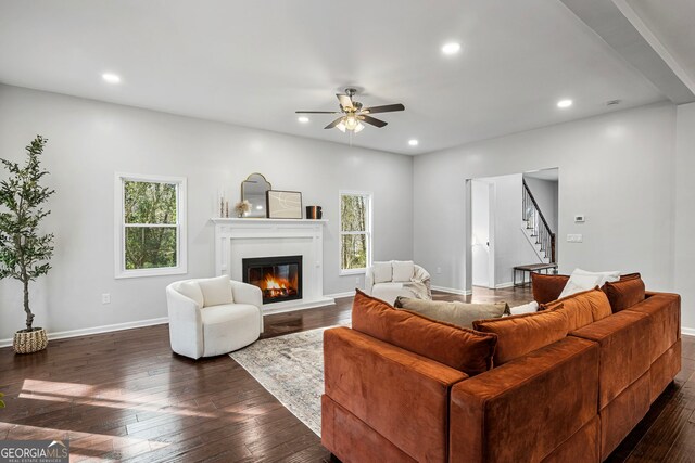 living area featuring dark wood-style floors, a glass covered fireplace, recessed lighting, and stairs