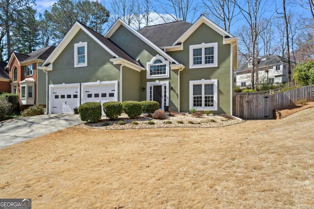 traditional-style house with stucco siding, an attached garage, concrete driveway, and fence