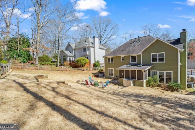 rear view of property with a shingled roof, a chimney, fence, and a sunroom