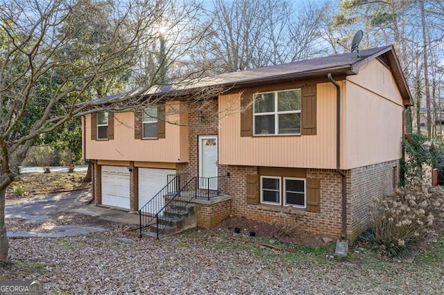 bi-level home with a garage, brick siding, and driveway