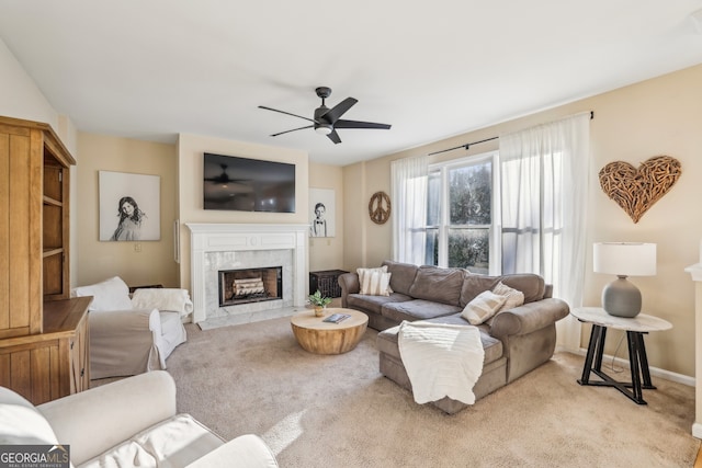 living area featuring a ceiling fan, baseboards, a high end fireplace, and carpet floors