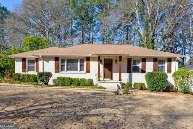 ranch-style house featuring brick siding and roof with shingles