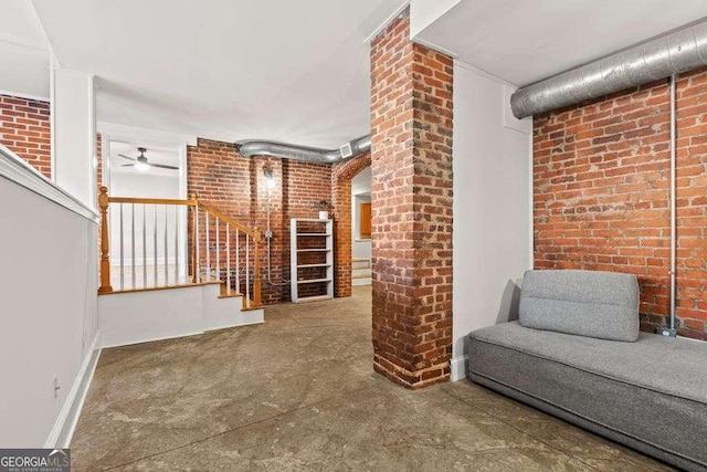 interior space featuring concrete flooring, brick wall, stairs, and a ceiling fan