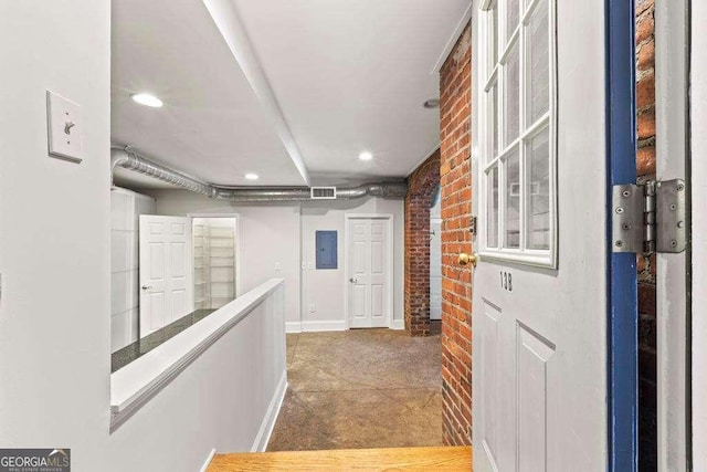 hall with visible vents, brick wall, baseboards, electric panel, and recessed lighting