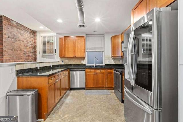 kitchen featuring brick wall, decorative backsplash, brown cabinets, stainless steel appliances, and a sink