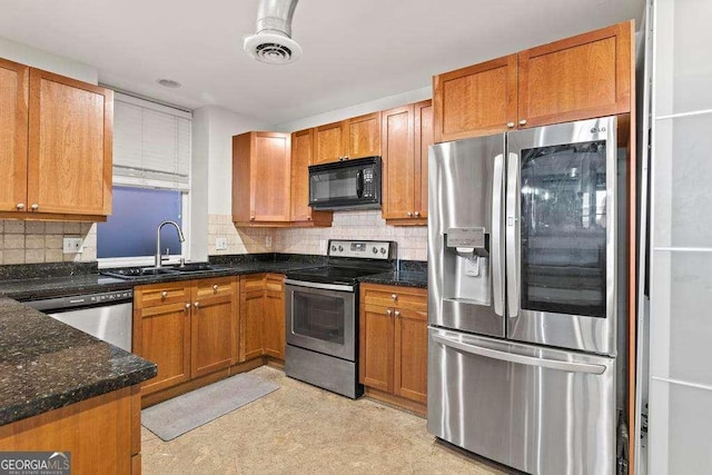 kitchen with a sink, dark stone countertops, backsplash, stainless steel appliances, and brown cabinetry