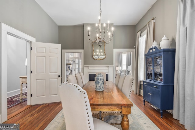 dining area featuring a notable chandelier, dark wood-type flooring, and a fireplace