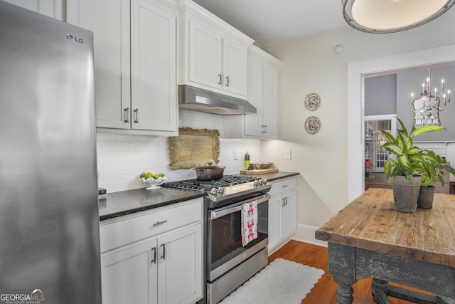 kitchen featuring stainless steel appliances, dark wood-type flooring, under cabinet range hood, white cabinetry, and tasteful backsplash