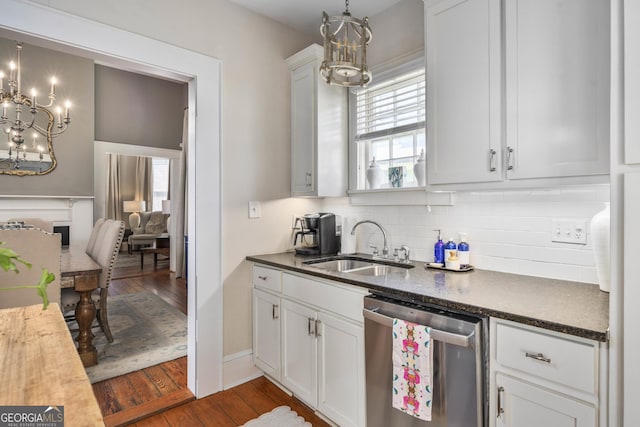 kitchen featuring tasteful backsplash, a fireplace, stainless steel dishwasher, dark wood-style floors, and a sink