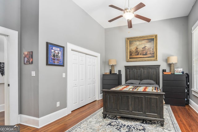 bedroom featuring a closet, baseboards, wood finished floors, and a ceiling fan