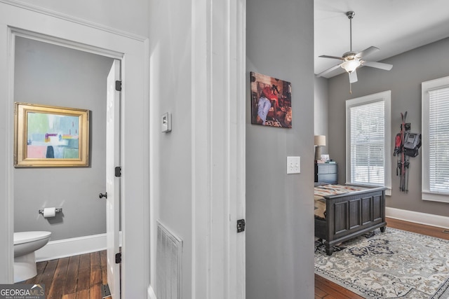 corridor featuring visible vents, baseboards, and wood finished floors