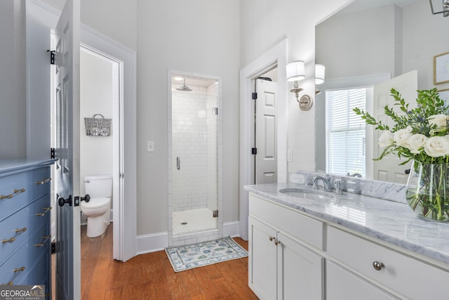 full bath with a stall shower, toilet, wood finished floors, and vanity