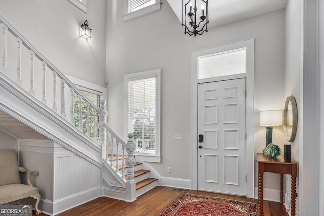 entryway with stairway, wood finished floors, visible vents, baseboards, and a notable chandelier