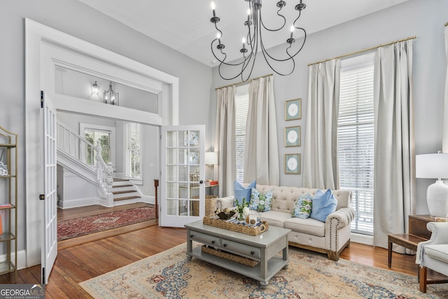 living room with stairway, a notable chandelier, and hardwood / wood-style flooring