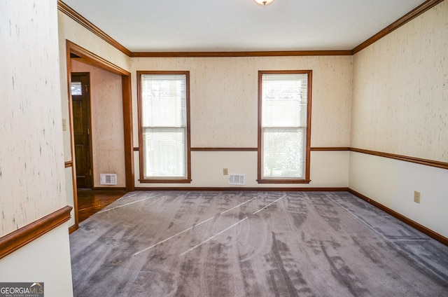 carpeted spare room featuring crown molding, baseboards, and visible vents