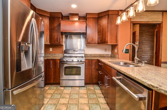 kitchen with light stone counters, custom exhaust hood, a sink, hanging light fixtures, and stainless steel appliances