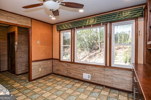 unfurnished room featuring wooden walls, visible vents, stone finish flooring, and a ceiling fan