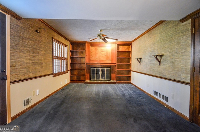 unfurnished living room featuring dark colored carpet, visible vents, a textured ceiling, and a glass covered fireplace