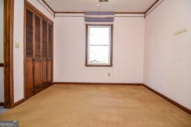 unfurnished bedroom with baseboards, visible vents, carpet floors, and ornamental molding