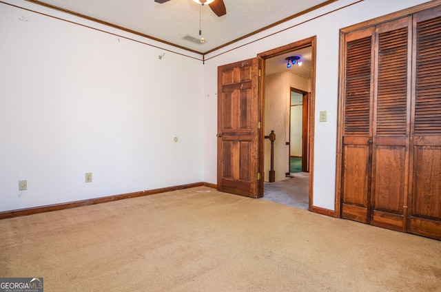 unfurnished bedroom featuring visible vents, crown molding, baseboards, carpet floors, and a closet