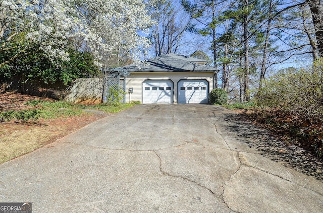 garage featuring driveway and fence