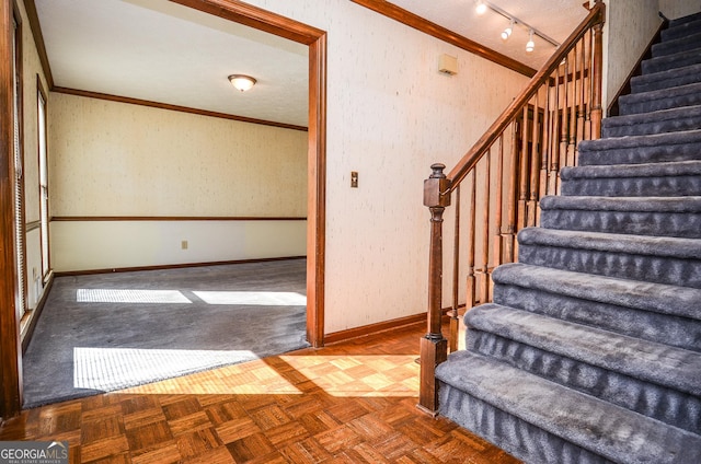 stairs featuring baseboards, ornamental molding, and track lighting