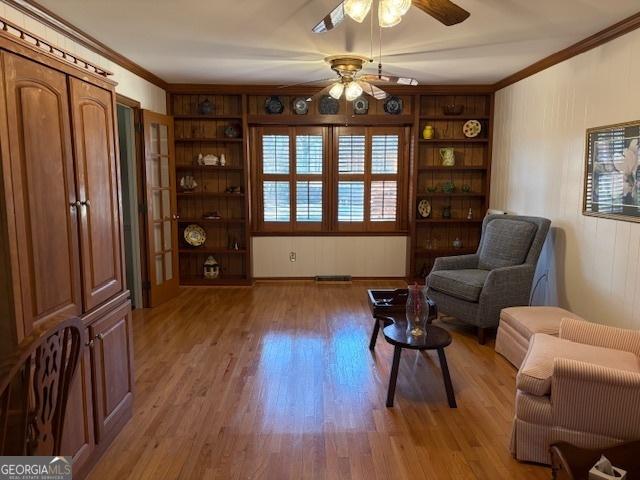 living area with light wood-type flooring, built in shelves, and ornamental molding