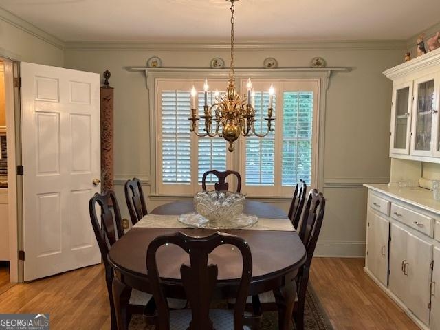 dining space with a chandelier, light wood-style flooring, and crown molding