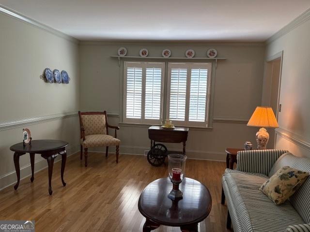 sitting room with ornamental molding, baseboards, and wood finished floors