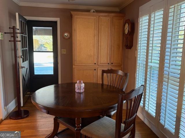 dining space featuring crown molding, baseboards, and wood finished floors