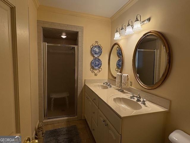 bathroom featuring a sink, ornamental molding, a shower stall, and tile patterned flooring