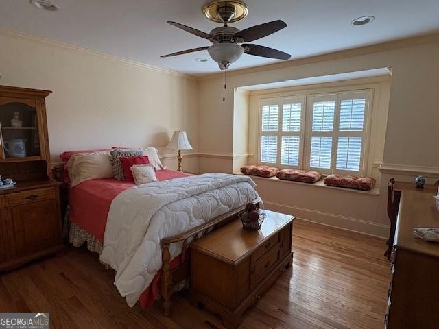 bedroom featuring light wood finished floors, ceiling fan, baseboards, and ornamental molding