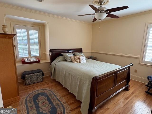 bedroom featuring light wood-style flooring, baseboards, ornamental molding, and a ceiling fan