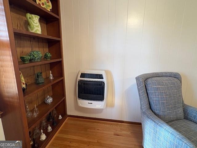 living area featuring heating unit, built in features, and wood finished floors