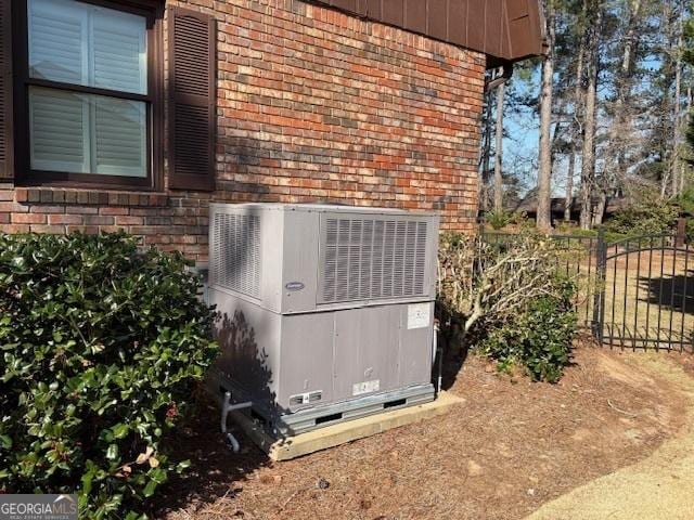 details with cooling unit, fence, brick siding, and crawl space